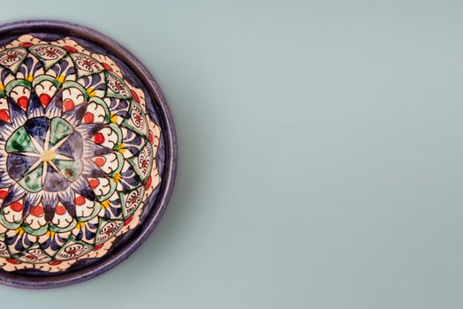 Ethnic Uzbek ceramic tableware on the gray background. Decorative ceramic cup with traditional uzbekistan ornament.