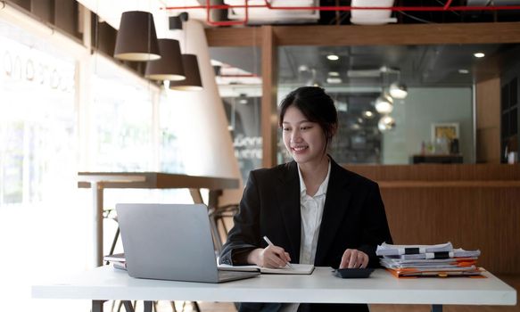 Young Asian businesswoman is happy to work at the modern office using a tablet..