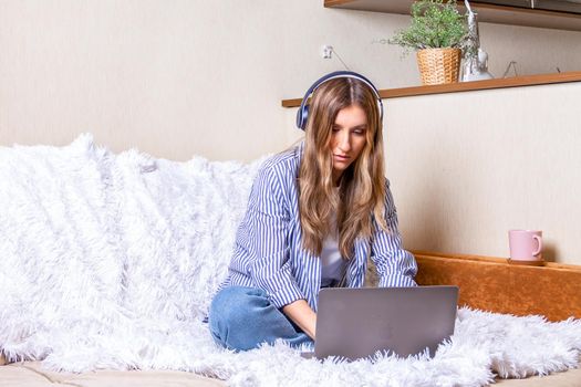 Home office woman and distance learning online education. Happy beautiful lady girl working at notebook sit on bed and drinking coffee at home. Using computer and online shops. With space for text