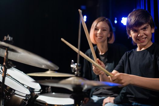 Young woman teaching boy to play drums