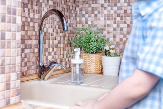 Blur kid hands in brown wooden kitchen sink with plants.