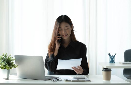 Beautiful young Asian businesswoman charming smiling and talking on the mobile phone in the office..