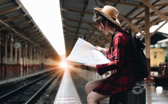 Young traveler woman looking on maps planning trip at train station. Summer and travel lifestyle concept.