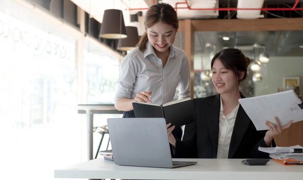 Two asian business woman work together to get the job done at the office..