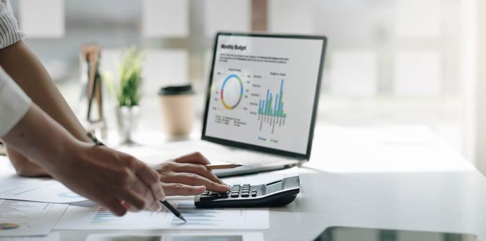 Businessmen use a calculator to calculate company financial statements for their colleagues, view and jointly solve problems within the company. Business finance and accounting concepts.