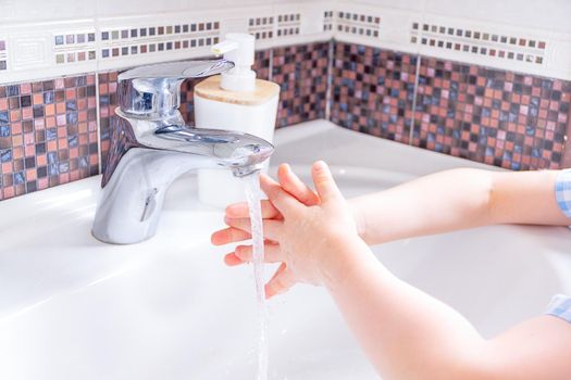 Washing hands with kid soap under the faucet with water. clean and Hygiene concept. Close up hands of kid