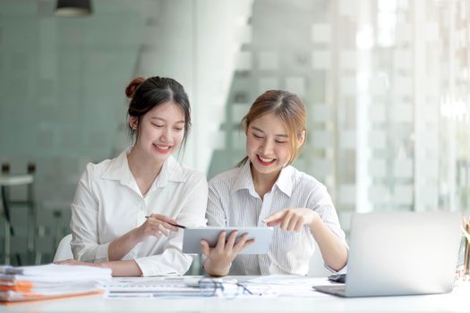 Two asian business woman work together to get the job done at the office..