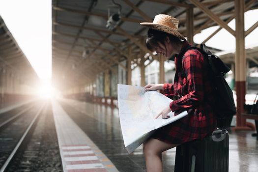 Young traveler woman looking on maps planning trip at train station. Summer and travel lifestyle concept.