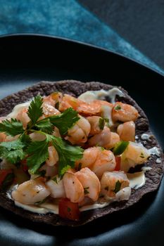 Red shrimp ceviche served with blue corn tostadas. Mexican food. Low key lighting on black and blue background