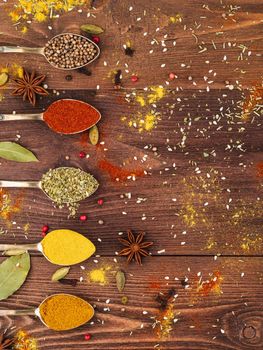 Set of spices in spoons on wooden background, top view. Concept for restaurant menu. Seasoning - paprika, curry, anise.