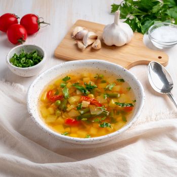 Healthy spring vegetable dietary vegetarian soup, white wooden background, side view, close up.