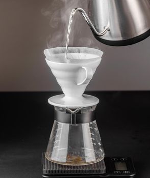 Alternative method of making coffee. coffeemaker is a manual pour-over style glass. Cofee brewing on black background