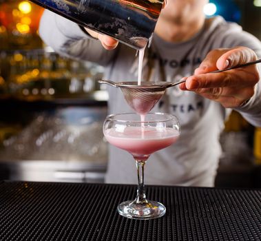 Expert barman is making cocktail at night club, Barman holds a cocktail in his hand. No face. Selective focus