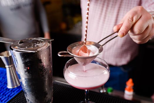 Expert barman is making cocktail at night club, Barman holds a cocktail in his hand. No face. Selective focus