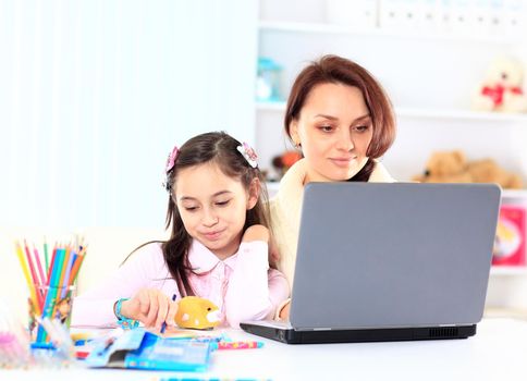 Young mother with little daughter sitting together at home