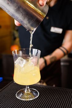 Expert barman is making cocktail at night club, Barman holds a cocktail in his hand. No face. Selective focus