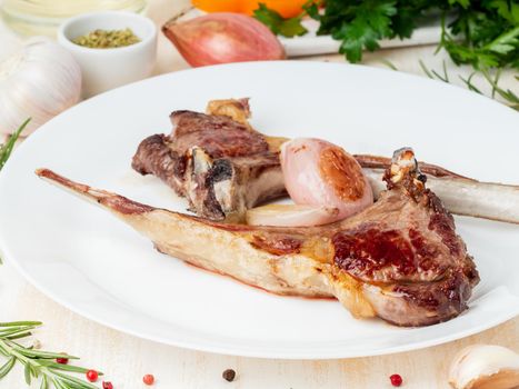 ketogenic, paleo, lchf diet - fat fried lamb ribs on white plate with vegetable and seasoning on white marble table, side view