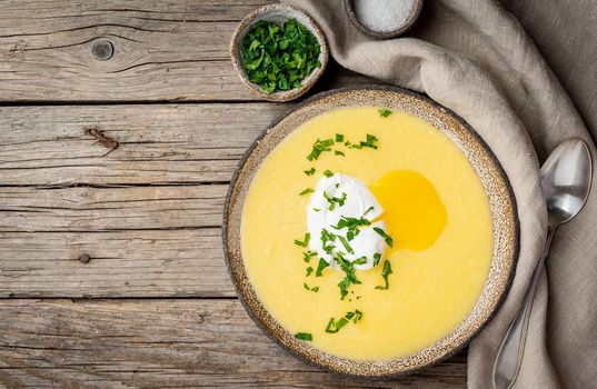 Polenta, porridge with Parmesan cheese and poached egg, on old dark wooden background, top view. traditional Italian cuisine