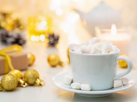 Cocoa with marshmallow on Christmas background. Cozy evening, cup of drink, Christmas decorations, candles and lights garlands.