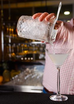 Expert barman is making cocktail at night club, Barman holds a cocktail in his hand. No face. Selective focus