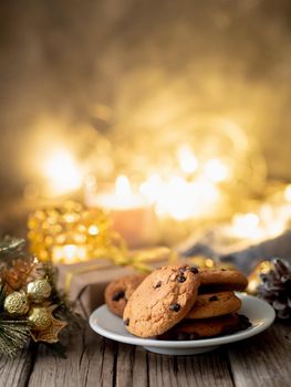 Chocolate chip cookies on dark christmas background. Cozy evening, Christmas decorations, candles and lights garlands