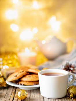 Christmas background with Chocolate chip cookies, cup of tea. Cozy evening, mug of drink, Christmas decorations, candles and lights garlands.