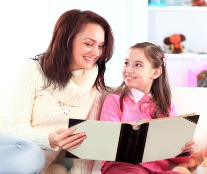 Happy mother and daughter reading a book together