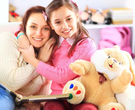 Happy mother and daughter reading a book together