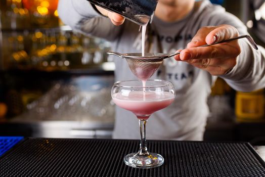 Expert barman is making cocktail at night club, Barman holds a cocktail in his hand. No face. Selective focus