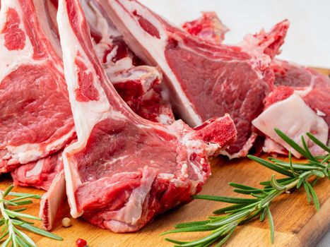 Raw lamb ribs on wooden chopping Board on old rustic wooden background, side view