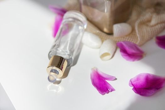 Natural cosmetics, a beautiful jar of fluid for the face on the background of pink petals from peonies