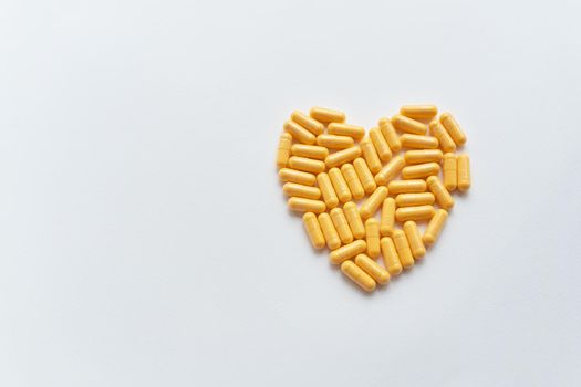 Heart shaped yellow pills, health and heart problems. Medicine and healthcare concept. Place for an inscription