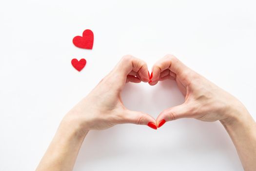 Female hands in the shape of a heart isolated on a white background, side view of small red hearts