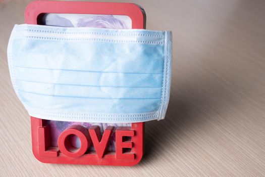 a frame with a photo of a young couple in love is covered with a medical mask.