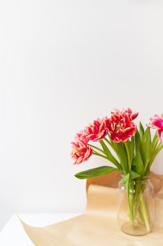 A beautiful spring bouquet of tulips stands in a vase. Surprise concept, birthday. Vertical photo, place for an inscription