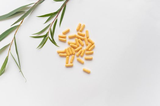 Yellow tablets of nutritional supplements lie on a white background. Place for an inscription. Green line in the background