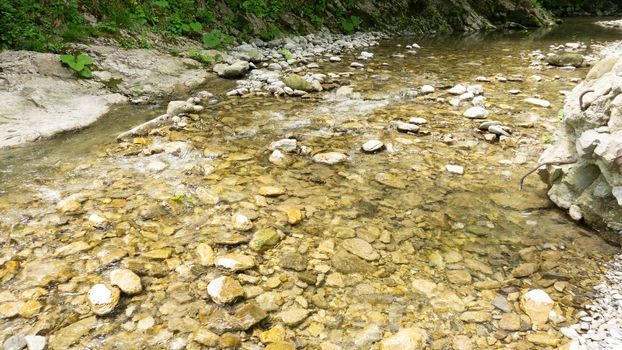 Mountain river among large stones in a green forest with small waterfalls. Sochi, Lazarevskoe, Berendeevo Tsarstvo, Russia