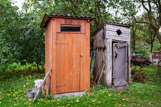 Old and next to it a renovated wooden toilet in the garden outside in the open air