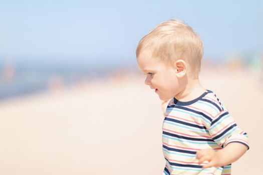 Little cheerful boy on the beach on a sunny summer day