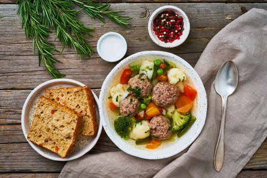 meatballs soup in white plate on old wooden rustic grey table, top view