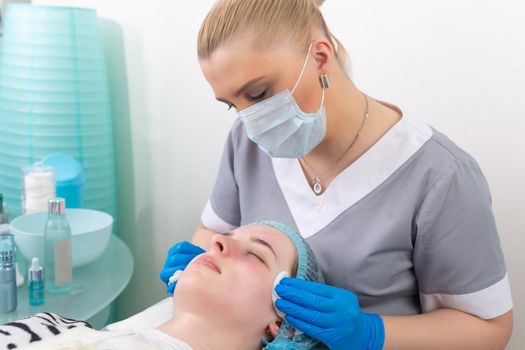 A female cosmetologist manually treats the patient's skin with a moisturizing and toning gel. The procedure helps to control the balance of fat content, restores the pH balance of the skin, gives a feeling of freshness and softness.