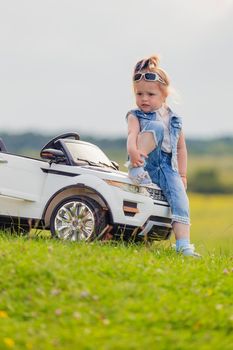 girl in sunglasses stands near the car in nature