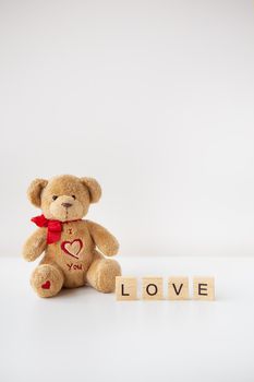 Valentine's day teddy bear and wooden letters with the inscription love. Place for an inscription