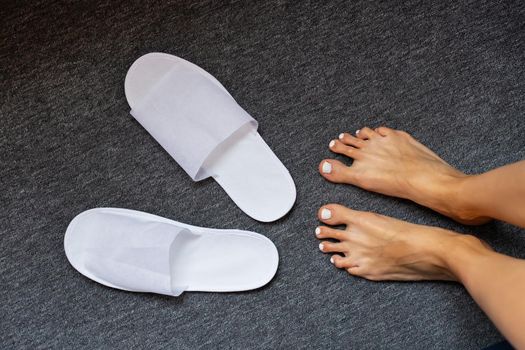 Comfortable and cozy white slippers on the rug, hotel accessories, top view