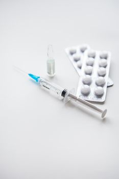 Preparation for vaccination against covid-19. Syringe, vaccine, pills, medical mask on a white table