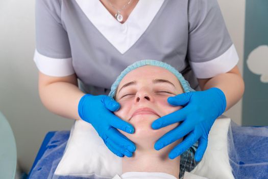 A female cosmetologist manually treats the patient's skin with a moisturizing and toning gel. The procedure helps to control the balance of fat content, restores the pH balance of the skin, gives a feeling of freshness and softness.