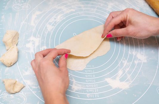 Dough preparation, cooking at home. Female hands roll out the dough on a silicone mat