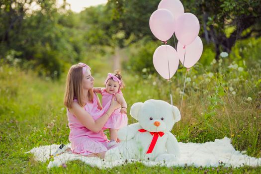 mother and daughter in pink dresses and with pink balloons in nature