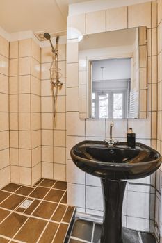 The interior of a cozy bathroom with beige tiles and a black ceramic sink in a modern apartment