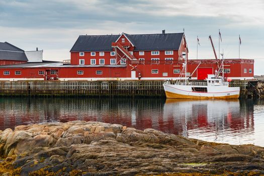 Cityscape of the town Henningsvaer, whaling and whaler boat, rocky coast with dramatic sky, classic view of Norwegian houses on the coast. High quality photo